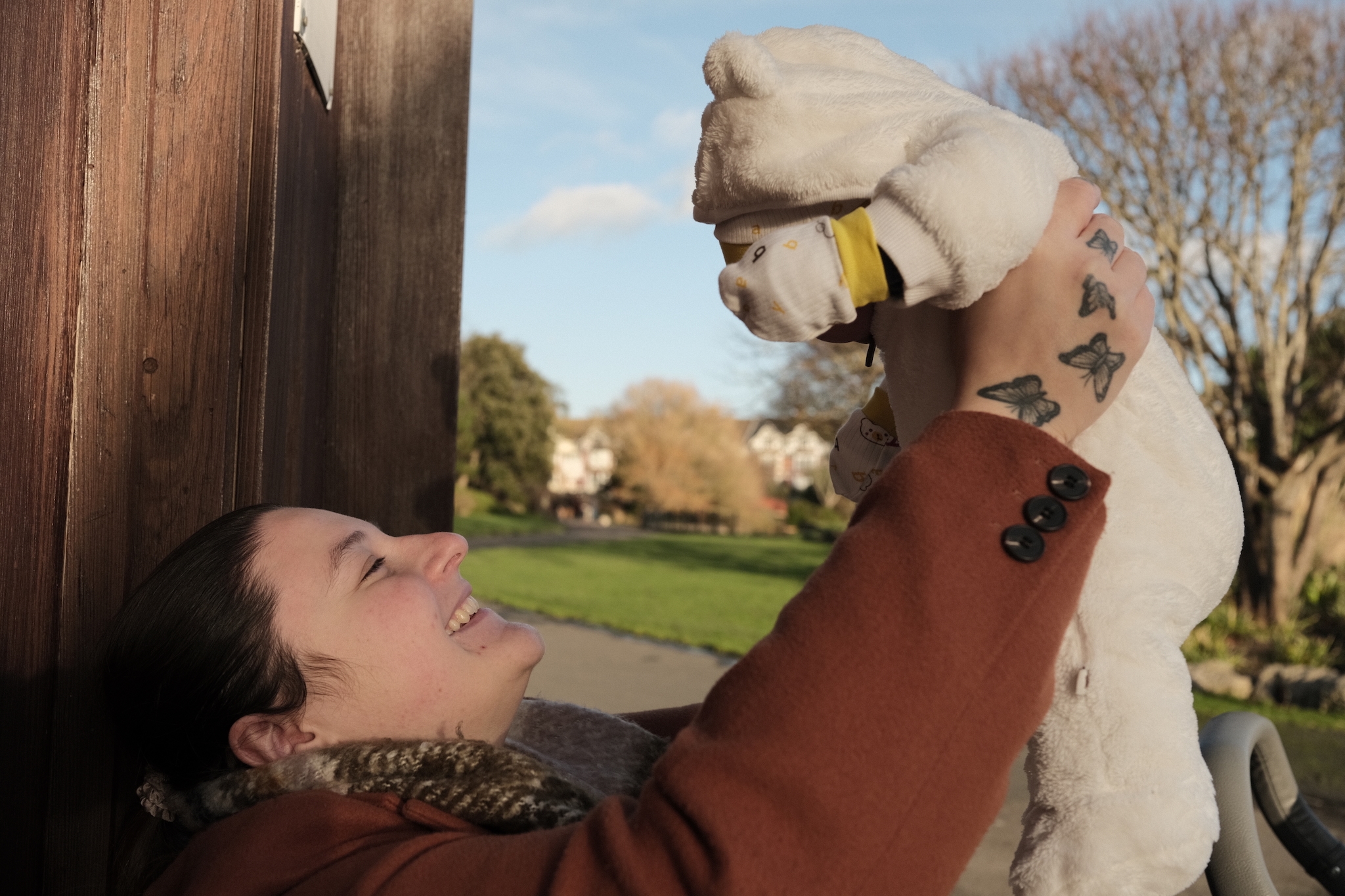 A woman holding her raising her baby in the air while looking at the her